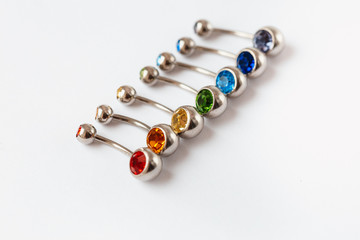 7 multicolored navel piercing earrings - red, orange, yellow, green, blue, indigo blue and purple. Macro closeup. Different focus points