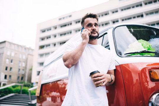 Bearded man leaning on car and calling