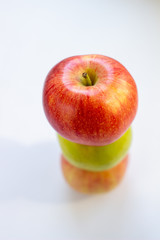 Three apples, one green and two red-yellow on a light background.