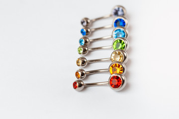 7 multicolored navel piercing earrings - red, orange, yellow, green, blue, indigo blue and purple. Macro closeup. Different focus points