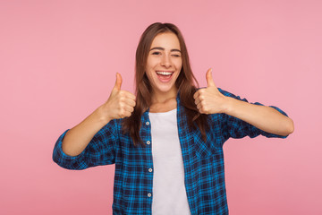 Well done! Portrait of enthusiastic girl in checkered shirt standing with double thumbs up and...