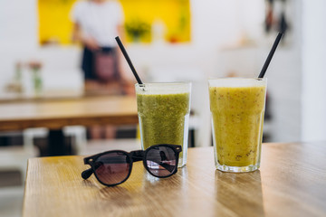Glass of tasty healthy smoothie on table in summer cafe.