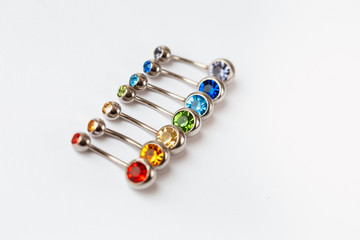 7 multicolored navel piercing earrings - red, orange, yellow, green, blue, indigo blue and purple. Macro closeup. Different focus points