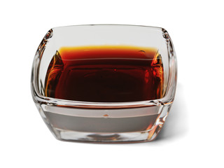 Soy sauce in a rectangular glass bowl, close-up. Isolated on a white background with a shadow