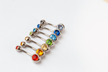 7 multicolored navel piercing earrings - red, orange, yellow, green, blue, indigo blue and purple. Macro closeup. Different focus points