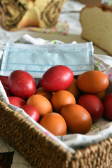 Wooden basket of Easter eggs with a protective face mask signifying celebration of Easter during...
