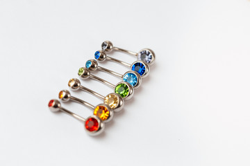 7 multicolored navel piercing earrings - red, orange, yellow, green, blue, indigo blue and purple. Macro closeup. Different focus points