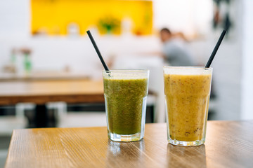 Two glasses of tasty smoothie on wooden table. Vegetable and fruit smoothies