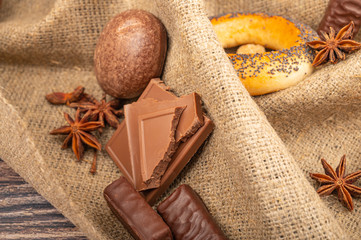 Bagels, chocolate, star anise and chocolate gingerbread on a background of coarse homespun fabric. Close up.