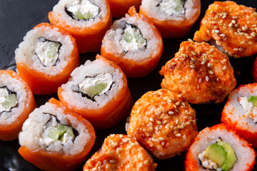 many sushi , set of Japanese rolls  Philadelphia with salmon,  California with caviar,    baked with  eel and .cheese , on a black