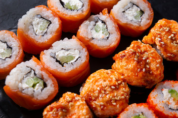 many sushi , set of Japanese rolls  Philadelphia with salmon,  California with caviar,  .cheese , baked with  eel ,  on a black   close up