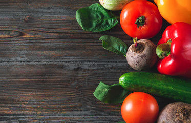 red and yellow peppers, beetroot, tomato, green cucumbers, garlic,  onions, spinach on a brown wooden  top view, fresh vegetables,  copy space