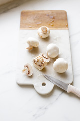 Fresh sliced champignon mushrooms on cutting board.