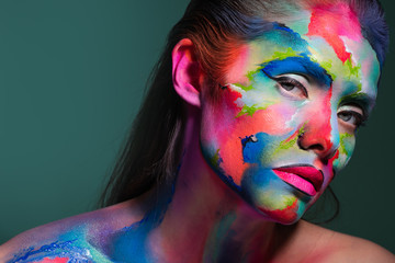 Face art and creative makeup, a young beautiful woman abstract art on the face
