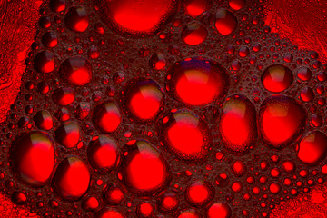 Abstract pattern from bubbles of oil in water. red color background close up