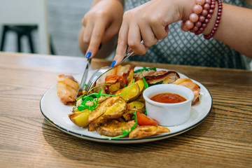 Woman tastes chicken in bacon with baked potatoes . Restaurant food, knife and fork