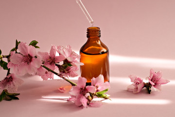Closeup bottle with peach essential oil on pink background.