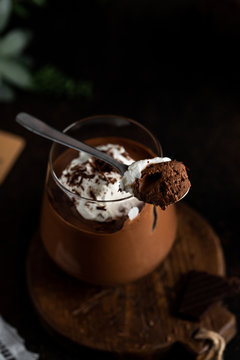 Chocolate mousse and whipped cream garnish with tablespoon top view dark and moody food photography