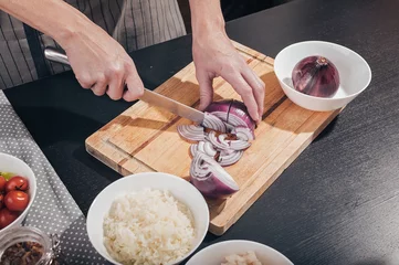 Foto op Canvas Female graceful hands cut red onion on a cutting board. Chef at work in the kitchen © yusev