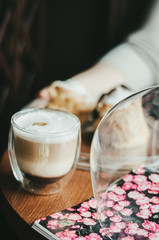 Beautiful speculoos latte with a foam of milk in a glass with coffee grains near it and some cookies. Lavender and another coffee in the back. Dark background