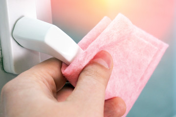 concept of disinfecting surfaces from bacteria or viruses cleaning door knob with disinfectant wet wipe. Disease prevention