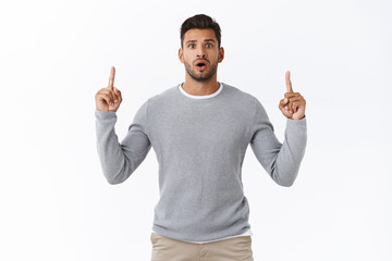 Shocked concerned worried handsome sexy guy in grey sweater, open mouth gasping holding breath from...
