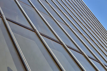 Close-up of many windows of a high-rise building with vertical dividing stripes. against the blue sky.