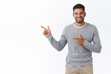 Good-looking charming bearded caucasian guy with short stylish hairstyle, wear grey sweater, pointing left, advertise product, corporate promotion, give advice or recommendation, smiling pleased