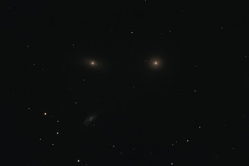 Fototapeta na wymiar The elliptical galaxy Messier 105, the lenticular galaxy NGC 3384, and the spiral galaxy NGC 3389 in the constellation Leo photographed with a Maksutov telescope from Mannheim in Germany.