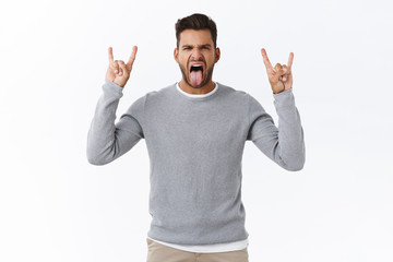 Fun, amusement and rock-n-roll concept. Good-looking overjoying modern guy enjoy music festival, show heavy metal gesture and tongue, squinting sassy, carefree feeling at concert, white background