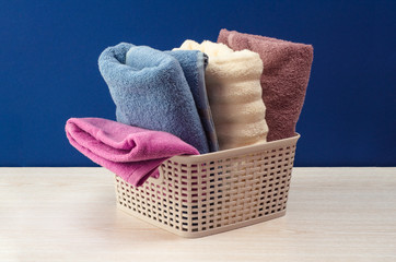 Bath towels of different colors in wicker basket on blue background