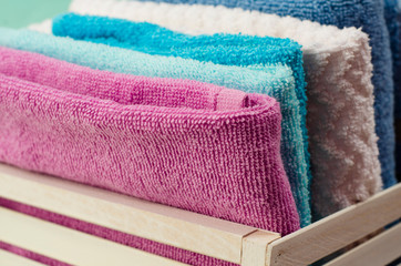 Bath towels of different colors in wicker basket on light background. Close up