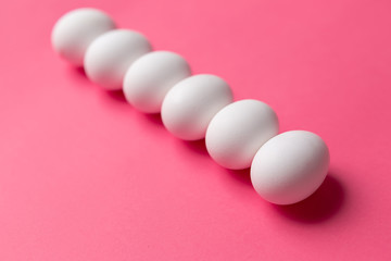 ten white eggs on a pink background