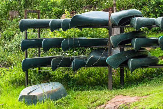 green canoe kayak boats on shelves outdoors for recreational activity or sport