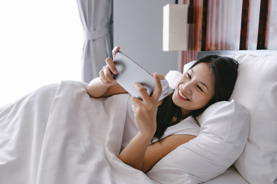 Woman with mobile phone on bed