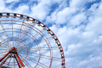 Red and White Ferris Wheel Against Blue and Cloudy Sky with Copy Space