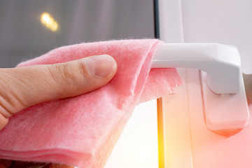 Wipes the door handle from the balcony disinfection. holds a cleaning cloth with antiseptic against the virus.