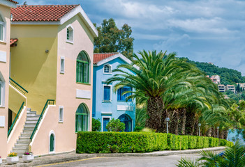 Summer landscape with beautiful tropical resort – colorful houses and palm trees. Corfu Island, Greece. 