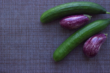 
Graffiti eggplant and smooth green cucumbers on a mesh kitchen napkin. Food Flat Lay