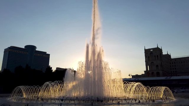 Baku, Azerbaijan - July 2019: Fountain in Baku National Seaside Park in front of the parliement building in the evening