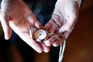 Mani tengono un orologio a cipolla con la catena e verificano l'ora, sfondo scuro 