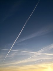 Fototapeta na wymiar Vapor trails in blue sky in the evening, symbol of air travel with copy space