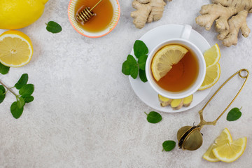 Ginger tea infusion in white cup with lemon slice, mint, honey. Hot healthy beverage on white background. Immune defence, vitamin c. Still life health care concept. Top view. Copy space.