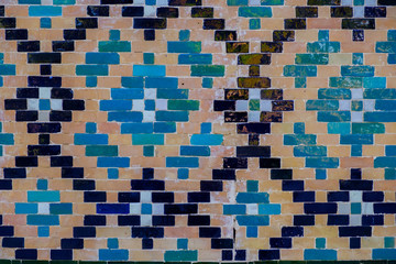 Tin-glazed pottery tiled wall in ancient mosque in Uzbekistan. Abstract art background.
