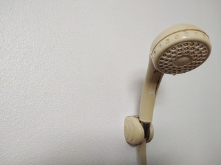 A shower room with a shower attached to the cement wall background.