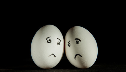 two sad eggs on a black background