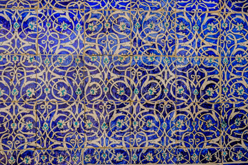 Maiolica style tin-glazed pottery tiled wall in ancient Khiva mosque in Uzbekistan. Abstract art background.