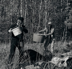 Two men collecting garbage while cleaning the forest, wearing mask for protection from corona virus covid-19.