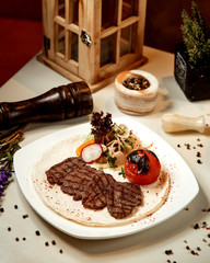 beef steak with tomatoes and seasoning in a plate