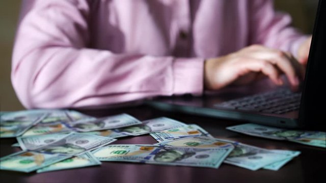 Office worker using laptop and getting paid in cash money